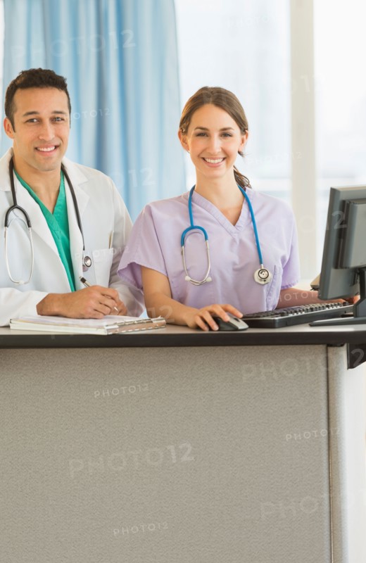 Portrait of male and female nurses at nurse's station in hospital.