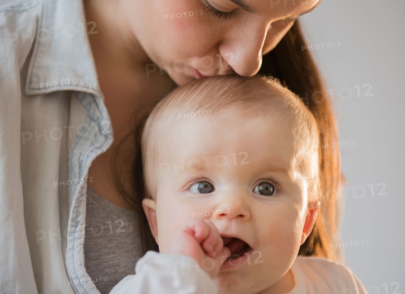 Mother kissing baby daughter (6-11 months)