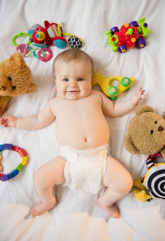Portrait of baby girl (6-11 months) lying down among toys