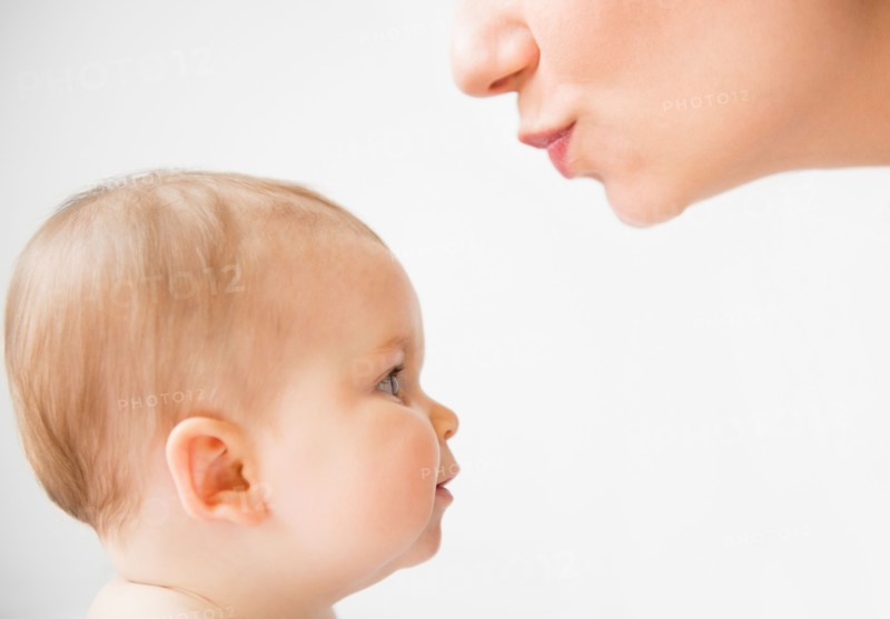 Side view of mother about to kiss her baby daughter (6-11 months)