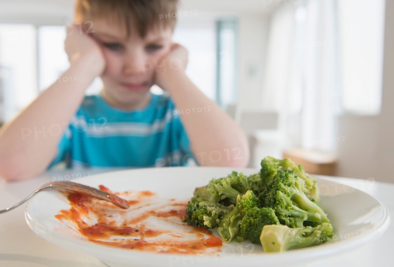 Portrait of boy (4-5) annoyed to eat broccoli