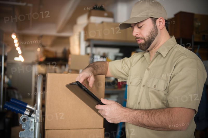 Delivery man in warehouse holding portable information device