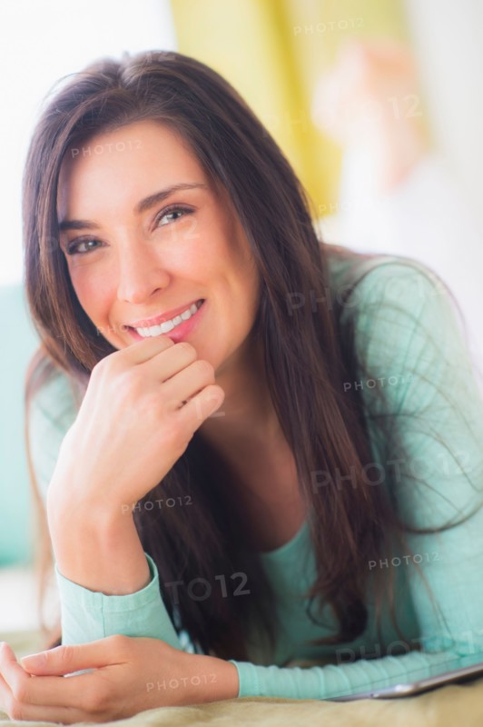 Portrait of woman lying down on bed with hand on chin, Close-up