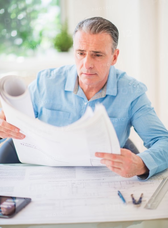 Portrait of man looking at blueprints in office