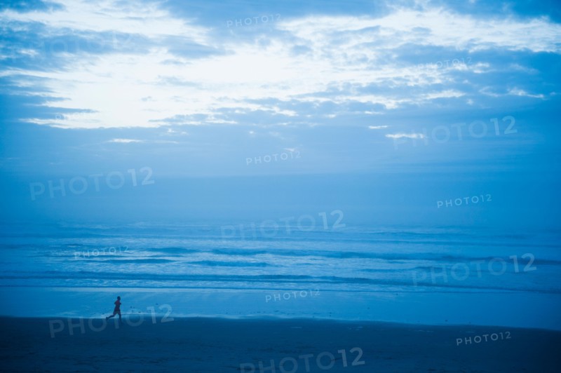 Distant view of woman running along beach