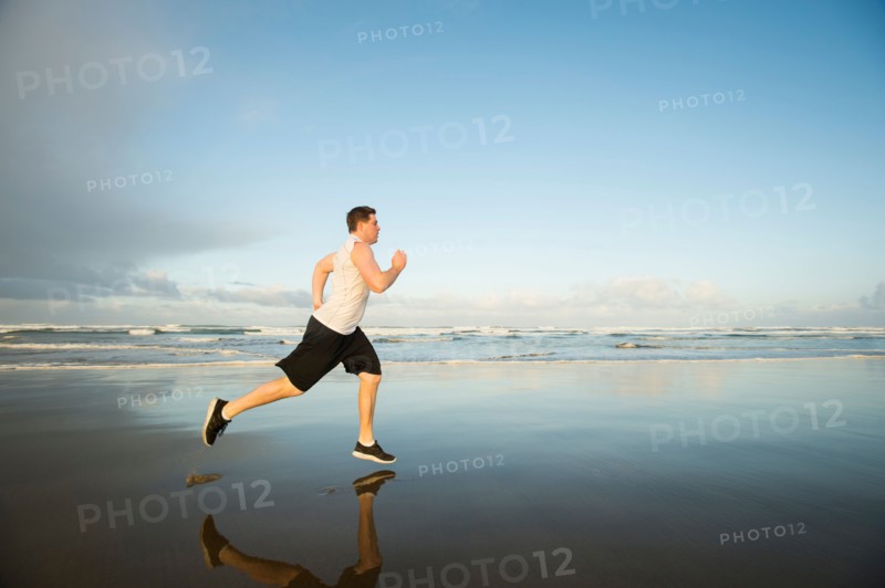 Young adult man running on beach