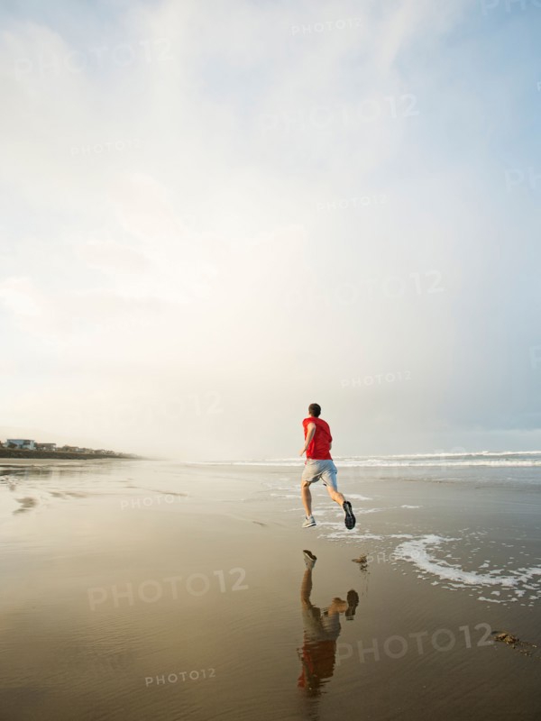 Young adult man running on beach