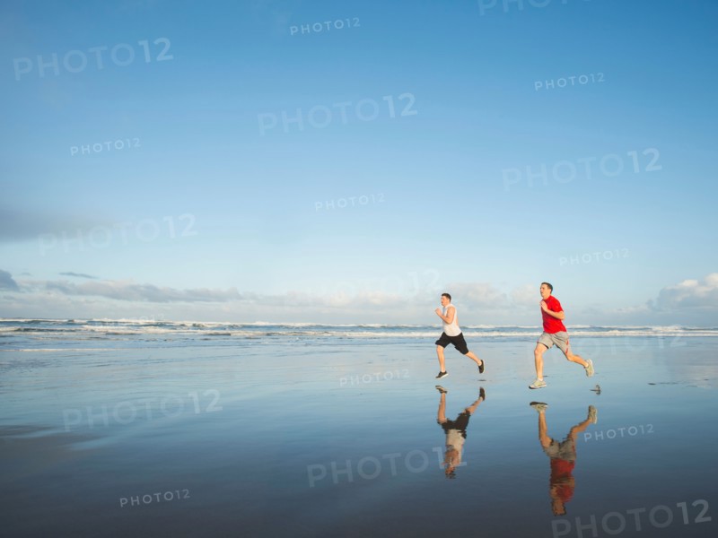 Young adult men running on beach