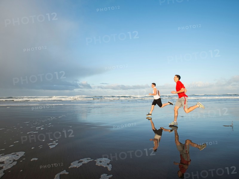Young adult men running on beach
