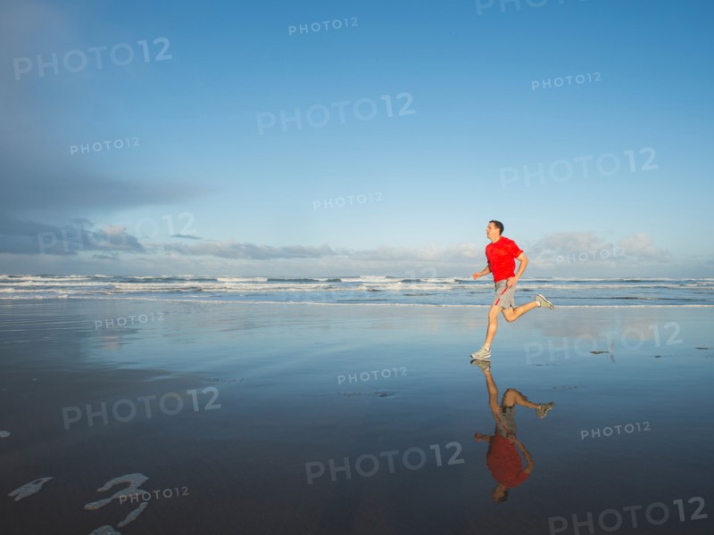 Young adult man running on beach