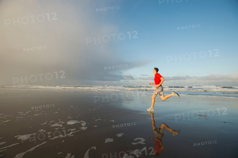 Young adult man running on beach