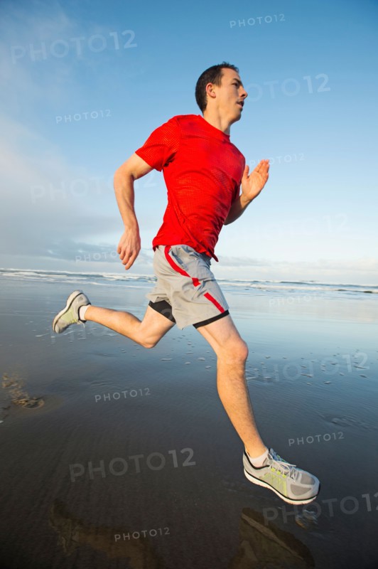 Young adult man running on beach