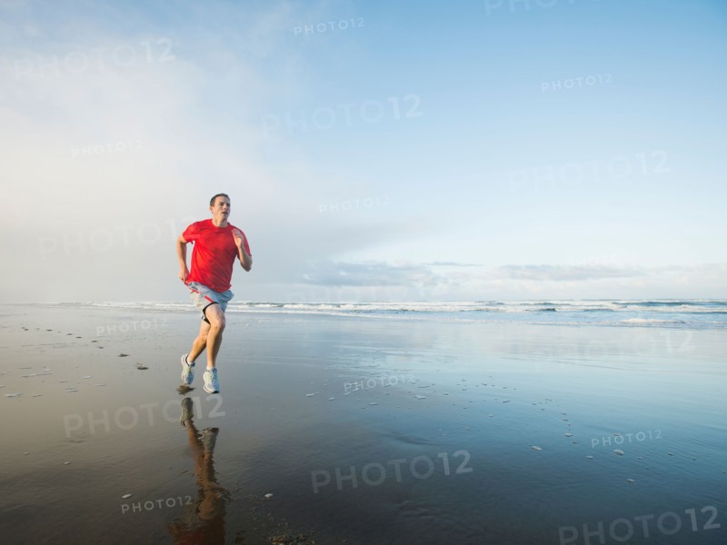 Young adult man running on beach