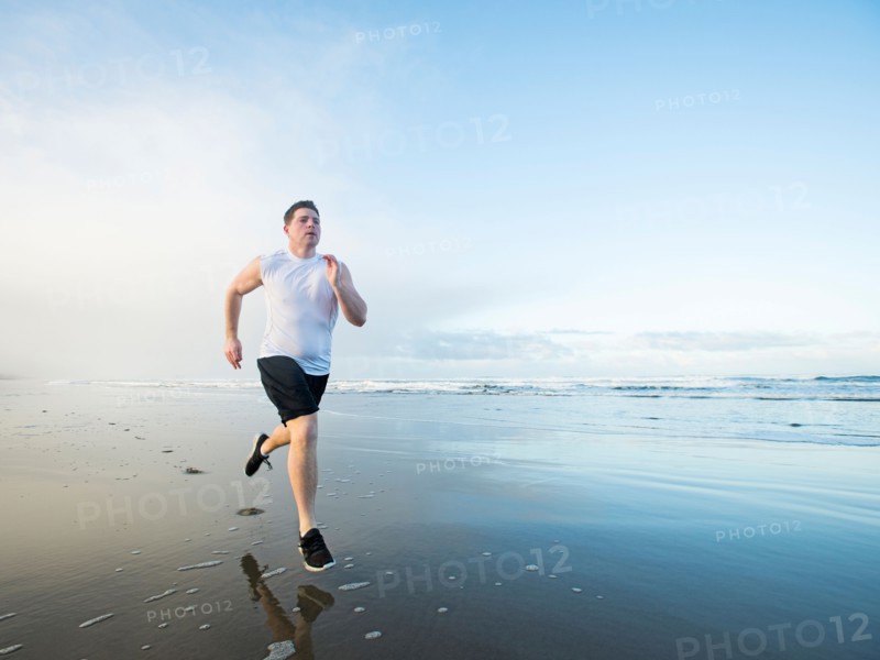 Young adult man running on beach