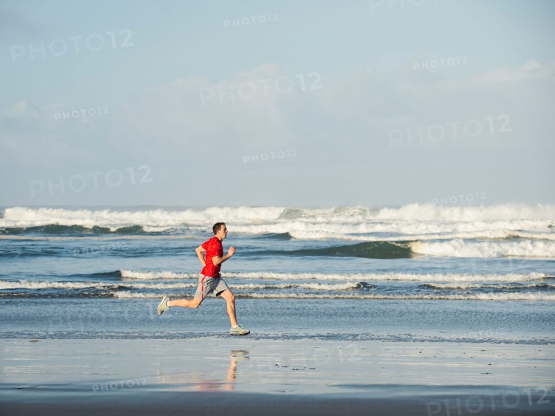Young adult man running on beach