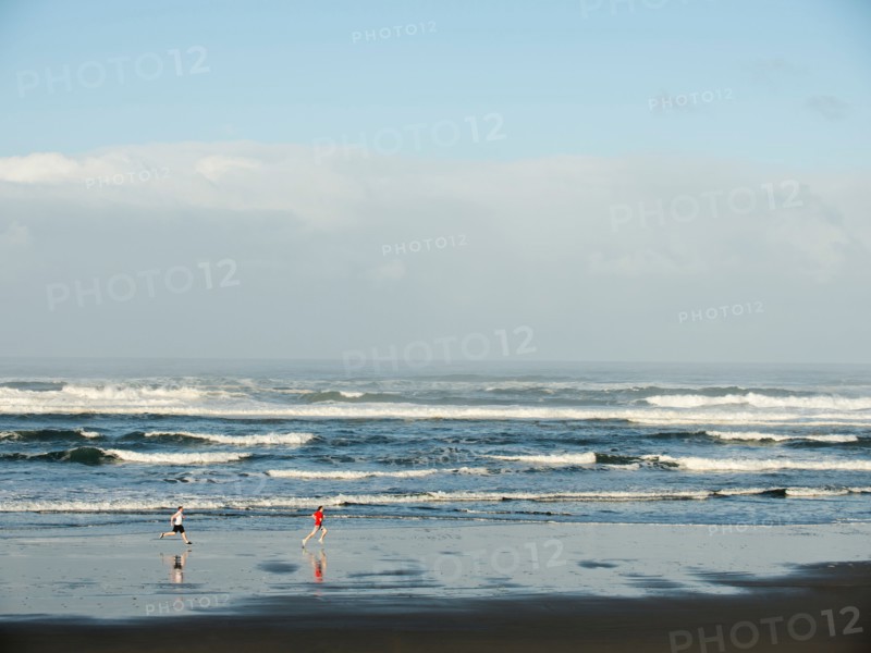 Young adult men running on beach