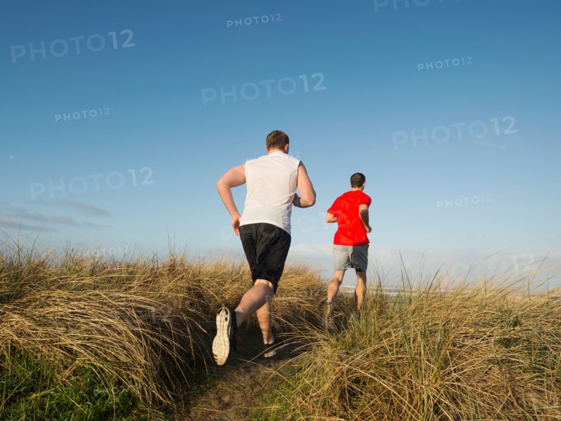 Young adult men running on dune