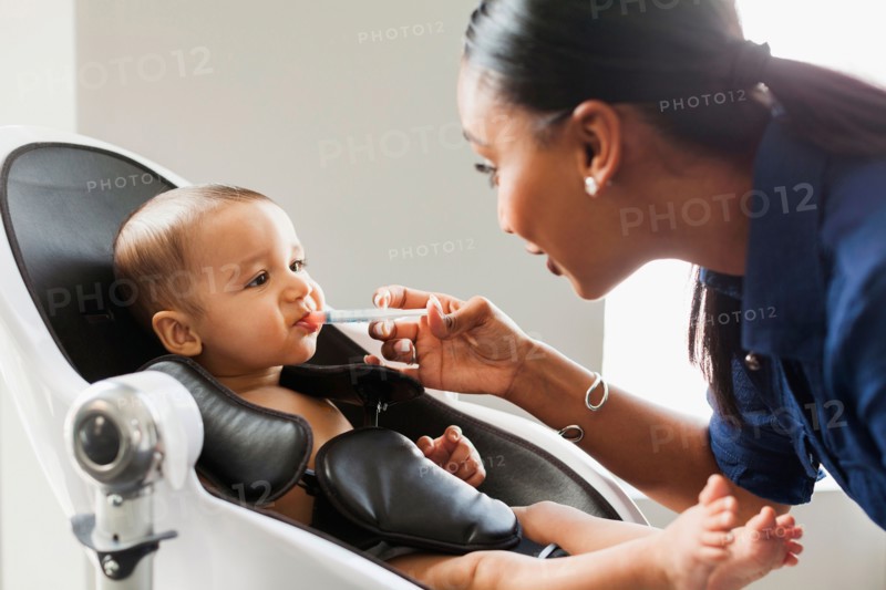 Mother giving medicine to baby (2-5 moths)