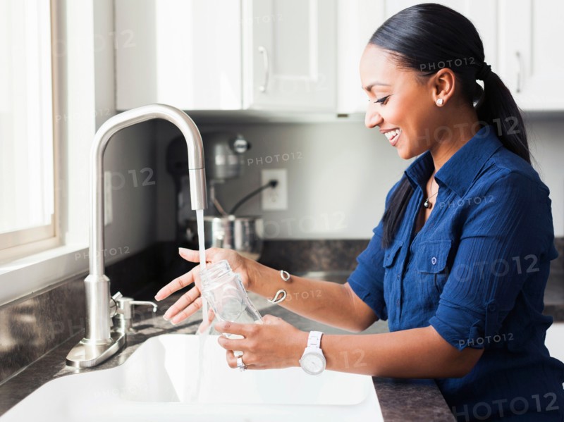 Woman washing baby bottle in kitchen