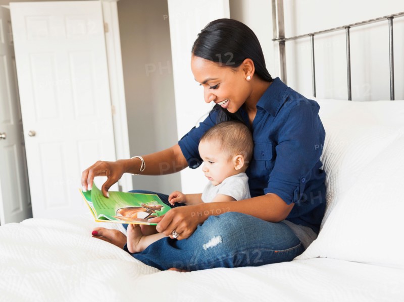 Mother showing her son (2-5 months) book and reading