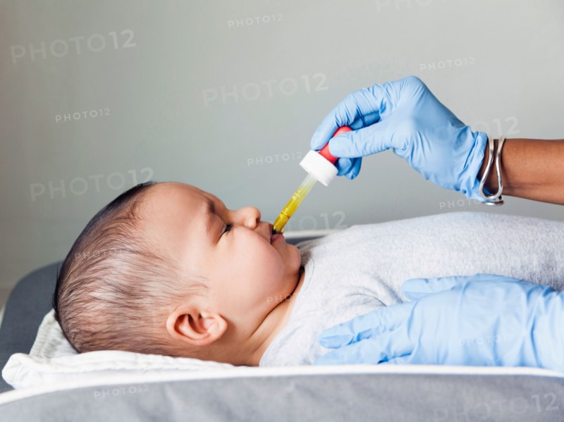 Nurse giving baby boy's (2-5 months) medicine using pipette