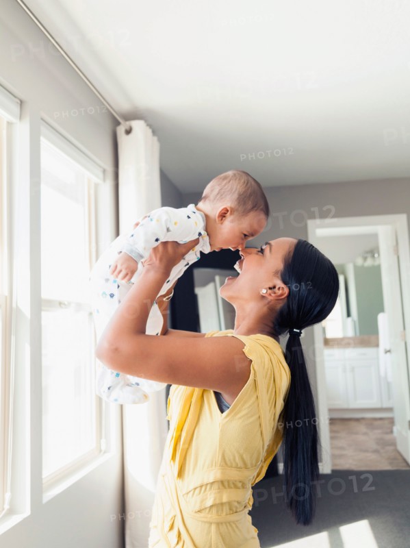 Woman holding up her baby son (2-5 months)