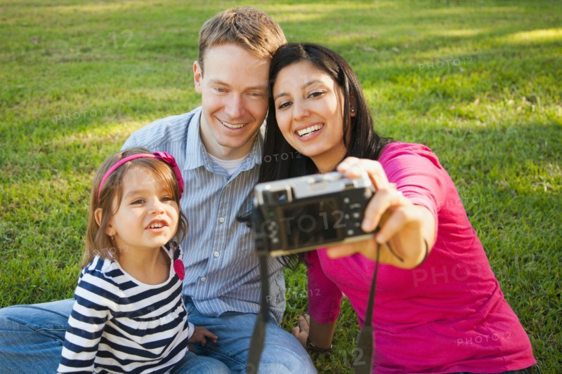 Family with daughter (4-5) playing in park and photographing themselves