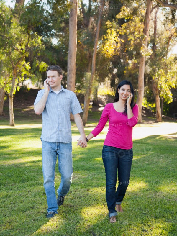 Couple walking and using mobile phone in park