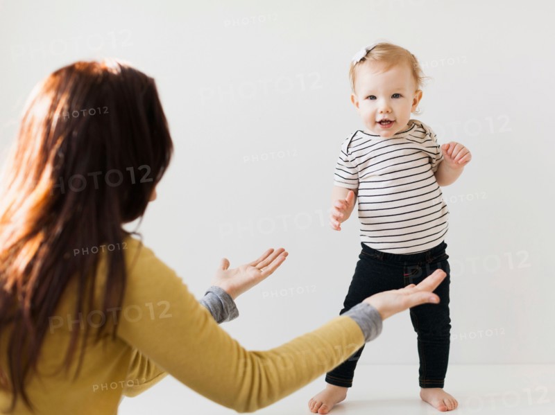 Mother raising hands towards her daughter (12-17 months)