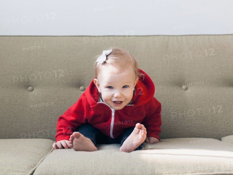 Portrait of baby girl (12-17 months) sitting on sofa