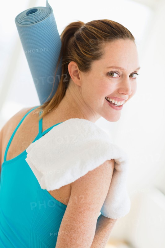 Woman carrying exercise mat and towel.