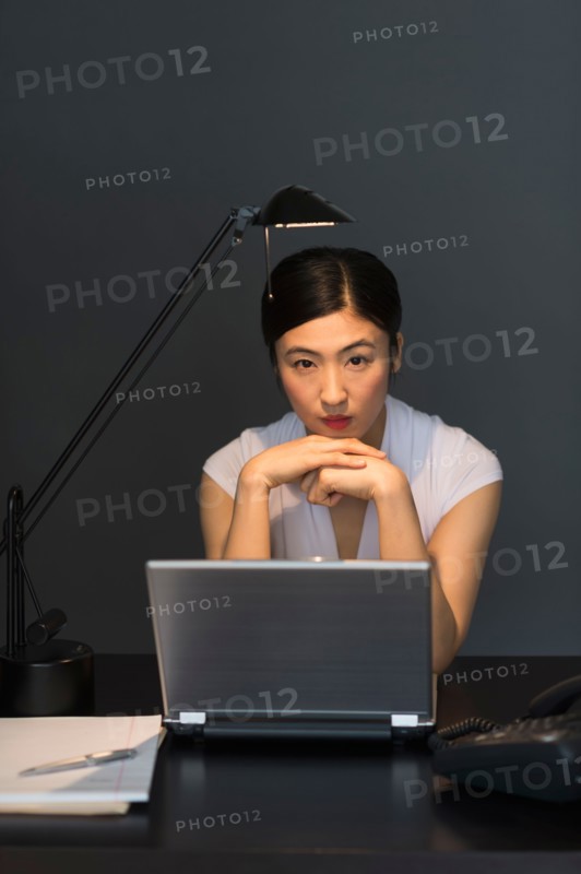 Businesswoman working on laptop at night.