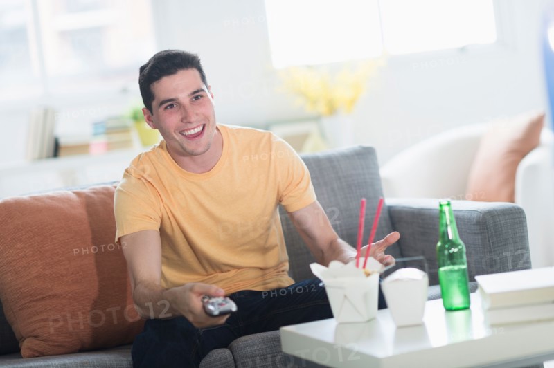 Man eating take out meal and watching television.