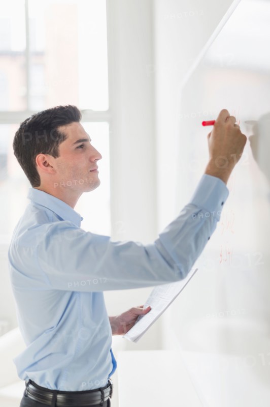 Businessman writing on whiteboard.
