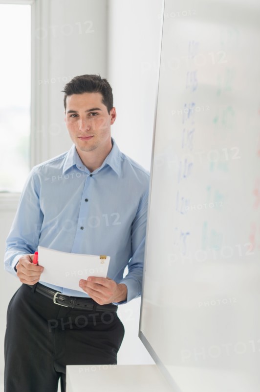 Businessman standing next to whiteboard.