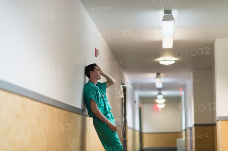 Tired doctor standing in hallway.