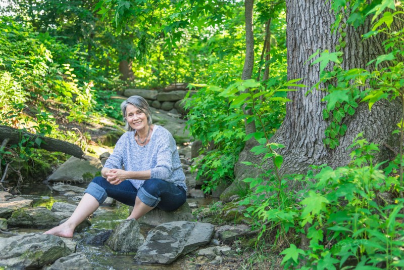 Central Park, New York City. Senior woman sitting on rock in forest.