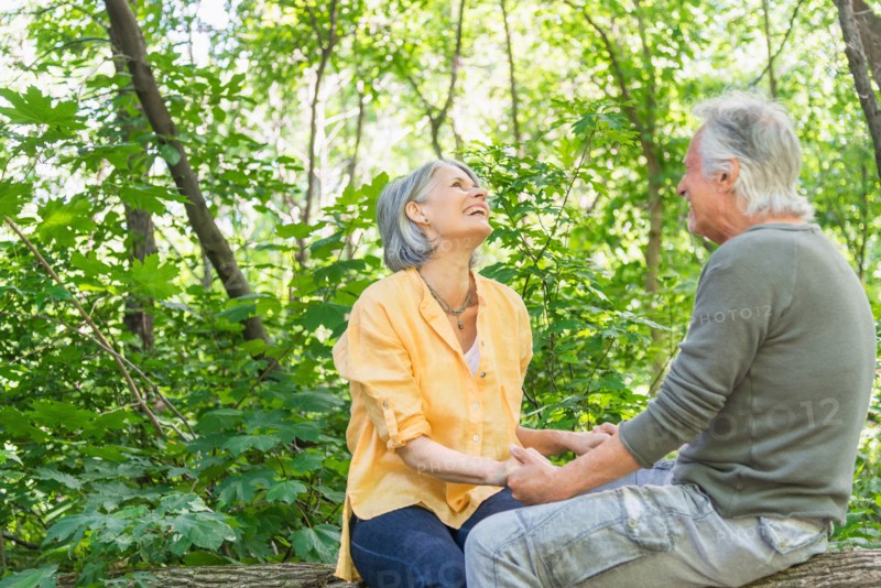 Central Park, New York City. Senior couple sitting on log in forest.
