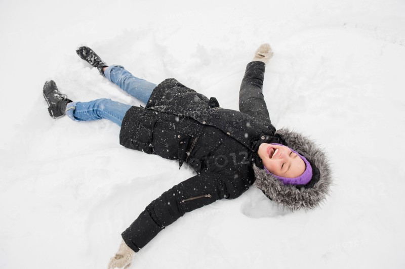 Young woman making snow angel