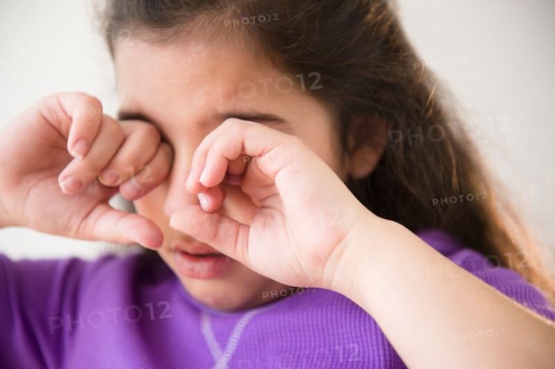 Girl (8-9) crying and covering eyes