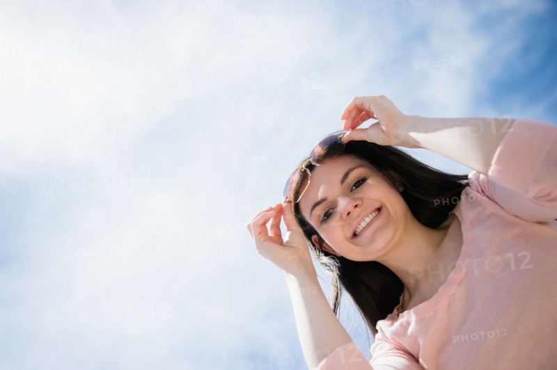 Portrait of young woman standing against cloudy sky