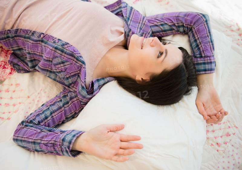 Portrait of relaxed young woman lying down on bed