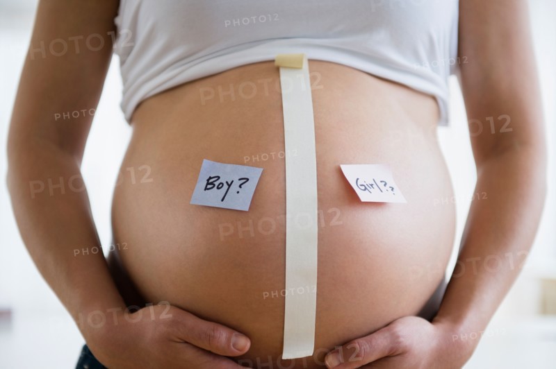Mid section of pregnant woman with name tags on belly