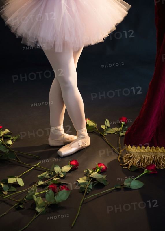 Teenage (16-17) ballerina on stage, roses by her feet