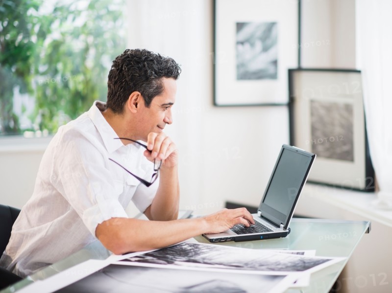 Portrait of man in his photography studio using laptop