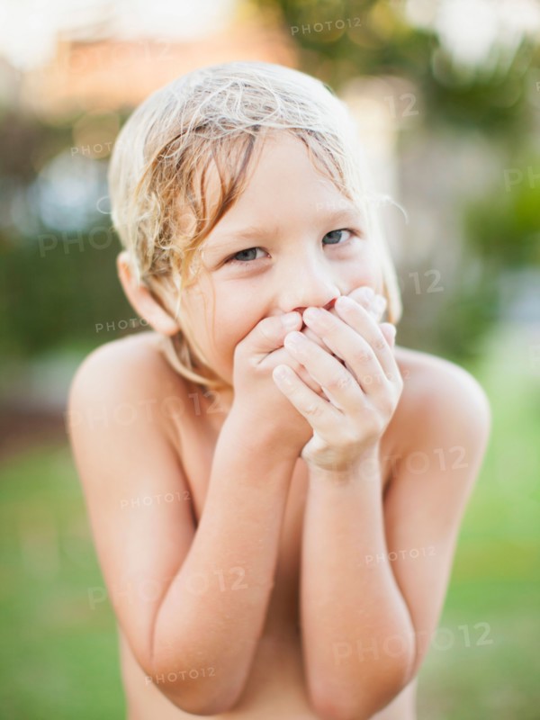 Portrait of boy (8-9) with hands covering mouth
