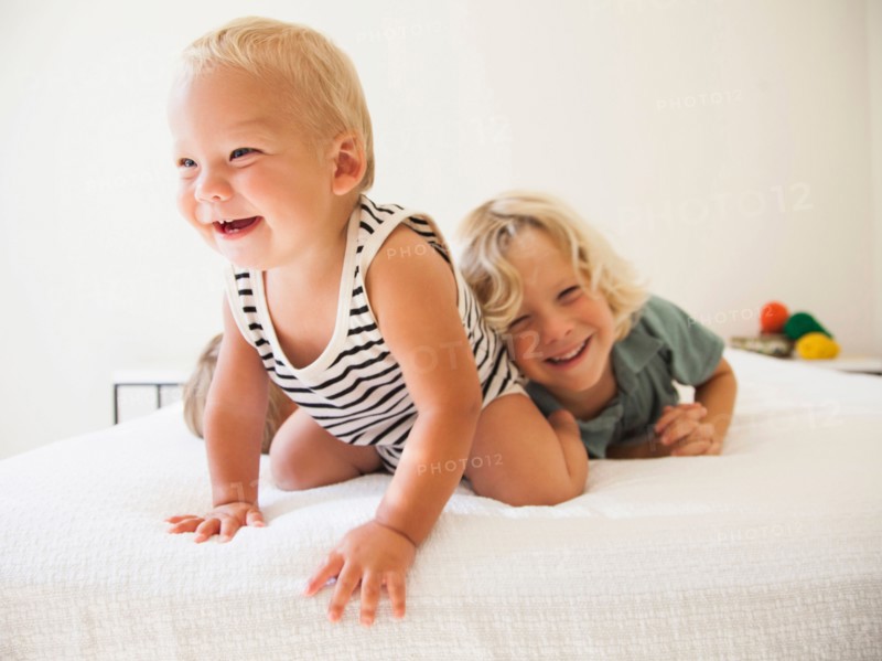 Boy (6-7) and girl (2-3) playing with their baby brother (6-11 months)