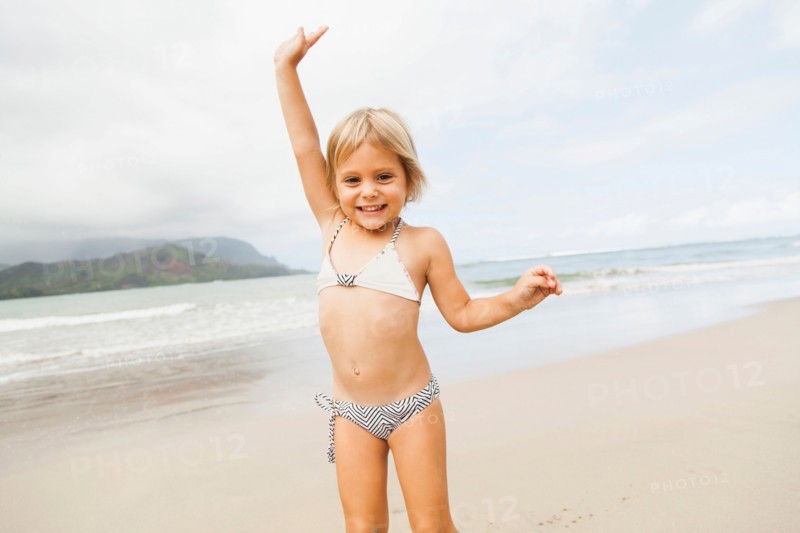 Smiling girl (2-3) on sandy beach