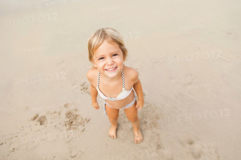 Smiling girl (2-3) on sandy beach