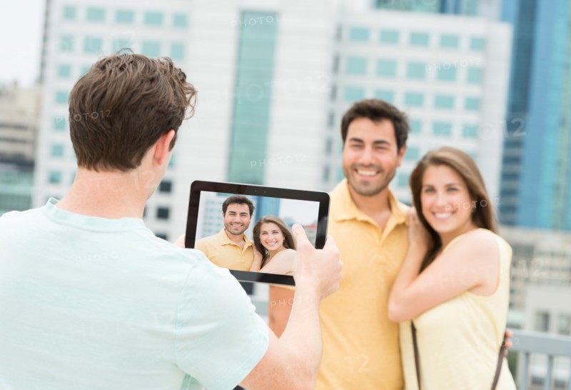 Man using tablet pc to take picture of friends.